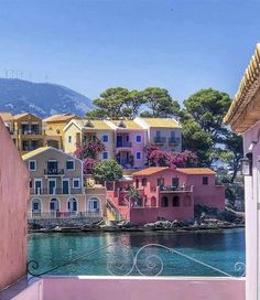 colorful houses line the water in front of mountains