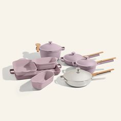 an assortment of pink pots and pans with wooden spoons on the side,