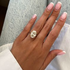 a woman's hand with a diamond ring on her left hand and white nails