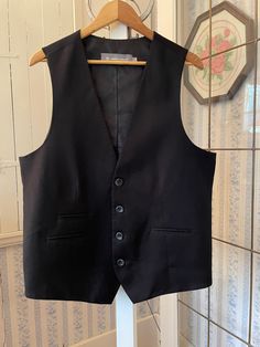 This beautiful vest was made by Linden Grey in a very soft blend of 54 per cent polyester, 44 per cent cotton and 2 per cent Lycra in classic black. It has the original buttons and three pockets in the front that haven't been used (they haven't been unsewn) and two tiny openings on the front left for a name tag to fit through. Marked size 44 regular. The measurements, taken with the vest lying flat, are: shoulder to shoulder, 15 inches; armpit to armpit, 23 inches; length, 28 inches in front and 24 1/2 inches in back; bottom edge, 23 inches. In very good condition. Wool Vest With Pockets For Work, Business Wool Sleeveless Vest, Winter Classic Sleeveless Blazer, Elegant Black Wool Vest, Formal Winter Sleeveless Vest, Sleeveless Black Blazer For Business, Sleeveless Black Business Blazer, Formal Sleeveless Winter Vest, Black Cotton Vest For Work