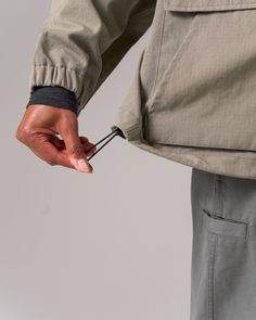 a person holding something in their hand and pulling on it with the other hand, against a gray background