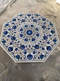 a blue and white tile table with flowers on it's surface in the process of being painted