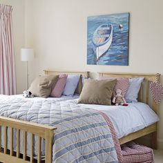 a bed sitting next to a window with pink curtains and pillows on top of it