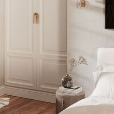 a white bed sitting next to a tall wooden cabinet in a bedroom on top of a hard wood floor