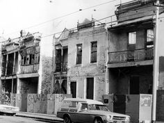 an old black and white photo of cars parked on the side of the road in front of buildings