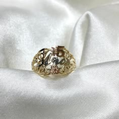 a gold ring sitting on top of a white satin fabric with the word love written in it