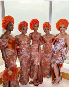 four women in orange dresses and turbans posing for the camera with each other