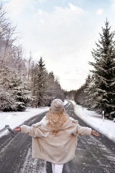 a woman is walking down the road with her arms spread out in front of her