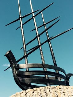 a large metal sculpture on top of a stone wall with spikes sticking out of it