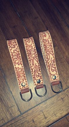 three pairs of leather straps sitting on top of a wooden floor