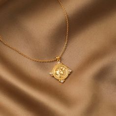 a gold necklace with a lion head on it and three small white stones in the center