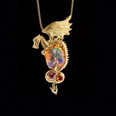 "Luminiferous Dragon soars into our one of a kind collection clutching a 10.5 carat Mexican fire opal. The stunning opal has been expertly sculpted to expose maximum play of color. Lavender, green and orange radiate from within. This precious opal is 6/8\" long x 5/8\" across. (19mm x 15mm) Luminiferous Dragon is lost wax cast in 18K gold. Luminiferous Dragon is detailed and three dimensional. A 4mm x 6mm pink sapphire and a 4mm x 6 Mexican Fire opal are set in the curves of the dragon's tail. I Gold Necklace With Dragon Design Collectible, Yellow Gold Dragon Design Jewelry Gift, Yellow Gold Jewelry With Dragon Design For Gift, Exquisite Gold Jewelry Collectible, Yellow Gold Dragon Pendant Jewelry, Luxury Gold Dragon Design Jewelry, Yellow Gold Dragon Design Pendant Jewelry, Luxury Gold Jewelry With Dragon Design, Unique Yellow Gold Collectible Jewelry