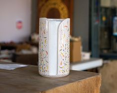 a white vase sitting on top of a wooden table