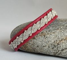 a red leather bracelet sitting on top of a rock