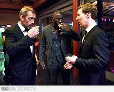 three men in tuxedos standing around talking to each other and drinking wine glasses