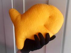 a hand holding a yellow stuffed animal on top of a white door handle with black gloves