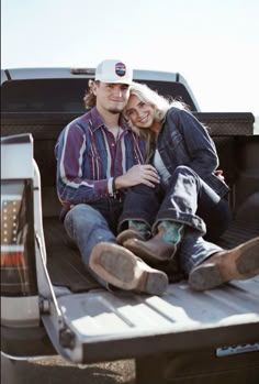 a man and woman are sitting in the back of a pick up truck with their arms around each other