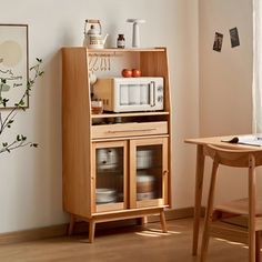 a small wooden table with a microwave on top of it in front of a window