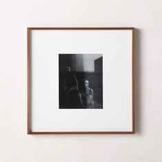 a black and white photo hanging on the wall next to a wooden frame with an image of two people