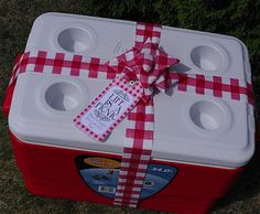 a red and white picnic cooler wrapped in paper with a bow tied around the top