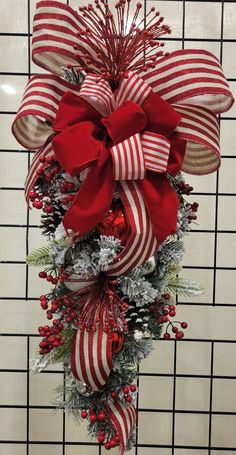 a red and white christmas wreath hanging on the side of a wall in front of a tiled wall