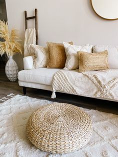 a white couch sitting on top of a wooden floor next to a vase filled with flowers