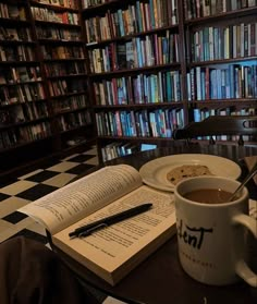 an open book on a table next to a cup of coffee