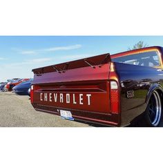 the back end of an old chevrolet truck parked in a parking lot with other cars behind it