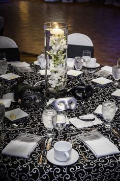 the table is set with white flowers and silverware