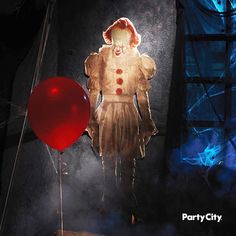 a creepy clown holding a red balloon in the dark