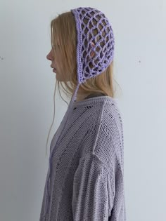 a woman with blonde hair wearing a purple knitted headband and looking off to the side