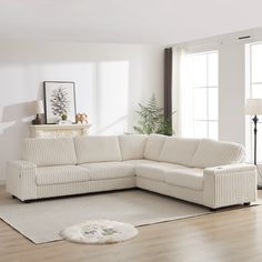 a living room with a white sectional couch and rugs on the hardwood flooring