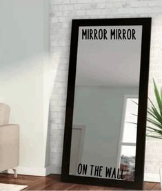 a large mirror sitting on top of a wooden floor next to a white chair and potted plant