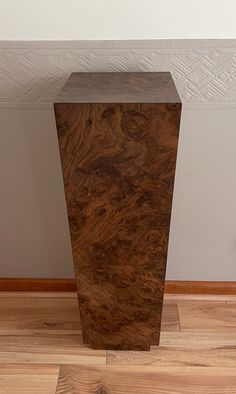 a tall wooden object sitting on top of a hard wood floor next to a wall