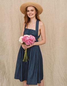 a woman wearing a straw hat and holding a bouquet of pink carnations in her hands