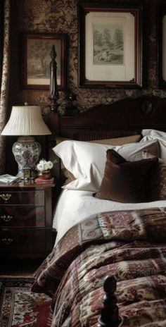 a bed sitting in a bedroom next to a lamp and pictures on the wall above it