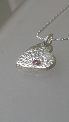 Made to Order: Handmade by Alison and finished by yours truly. Natural ruby (heat treated but not glass filled). Round cut with carat weight of 0.08ct that is bezel set. Lines lead out from ruby like a starburst. Pendant measures approximately 0.57 inches from top to bottom and 0.47 inches wide. Birthstone for July. Made of solid fine silver and comes with 18 inch sterling silver Cardano style chain with lobster clasp. Heart-shaped Jewelry With Bezel Setting For Valentine's Day, Heart-shaped Bezel Set Jewelry For Valentine's Day, Silver Birthstone Necklace With Heart Charm, Valentine's Day Jewelry With Bezel Setting, Ruby Heart Pendant Jewelry For Anniversary, Silver Heart Pendant Birthstone Necklace, Anniversary Ruby Jewelry With Heart Charm, Silver Jewelry With Birthstone For Valentine's Day, Silver Sterling Silver Heart Cut Birthstone Necklace