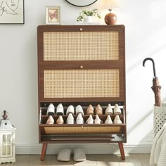 a wooden shoe rack filled with shoes next to a wall mounted clock and pictures on the wall