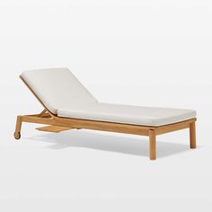 a wooden lounge chair with white cushions