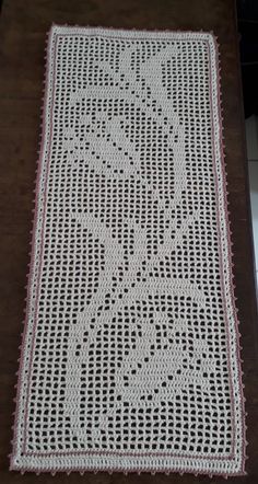 a white crocheted table runner with pink trim