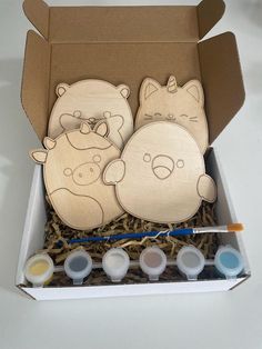 an open box with two wooden cutouts of animals in it and some paint tubes