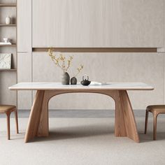 a dining table with two chairs and vases on it in front of a bookcase