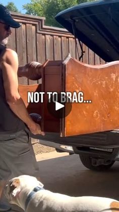 a man is unloading a wooden box from the back of a truck with his dog