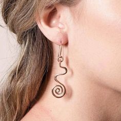 a close up of a woman's ear wearing gold earrings with spiral design on it