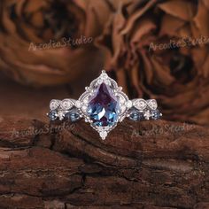 an engagement ring with blue and white stones on it, sitting on top of a piece of wood