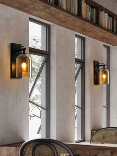 two tables and chairs in front of large windows with bookshelves on the wall