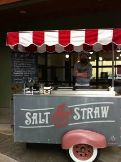 a man standing behind a gray and red food cart