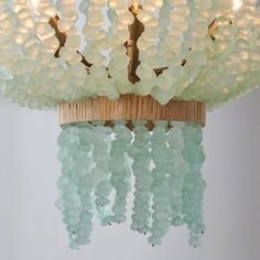 a chandelier made out of glass beads hanging from a wooden ceiling light fixture