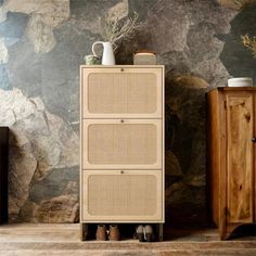 a tall cabinet sitting in front of a wall with rocks on the walls behind it