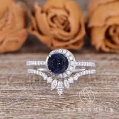 a blue and white diamond ring sitting on top of a wooden table next to roses